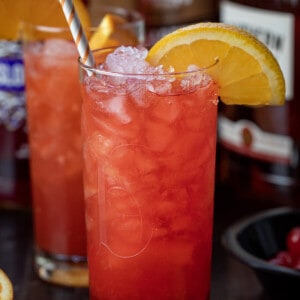 Alabama Slammer Cocktail on a Cutting Board with Oranges and a Straw.