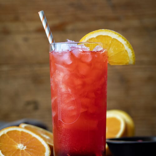 Alabama Slammer Cocktail on a Cutting Board with Oranges and a Straw.