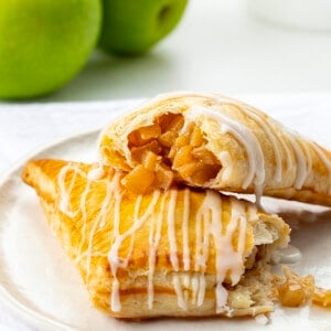 Apple Turnovers on a Plate with One Broken in Half and Apple Filling Spilling Out.