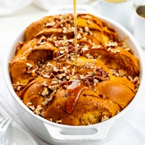 Adding Syrup to Pumpkin French Toast Casserole in White Pan on White Counter.