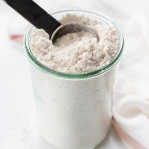 Glass Jar of Homemade Bisquick with a Measuring Cup Inside.