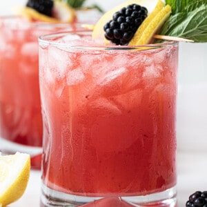 Blackberry Fizz Cocktails on a White Counter with Blackberry Lemon Garnish.