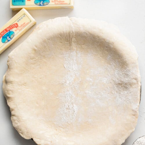 Butter Pie Crust Dough Laid on a Pie Pan Next to Butter.