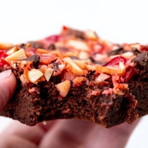 Hand holding bit into Cherry Chocolate Magic Brownies.