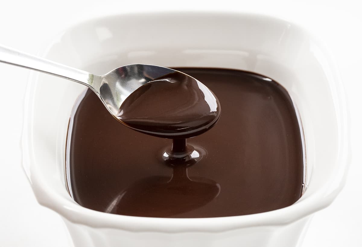 Spoonful of Homemade Chocolate Fudge Sauce that is in a White Square Container