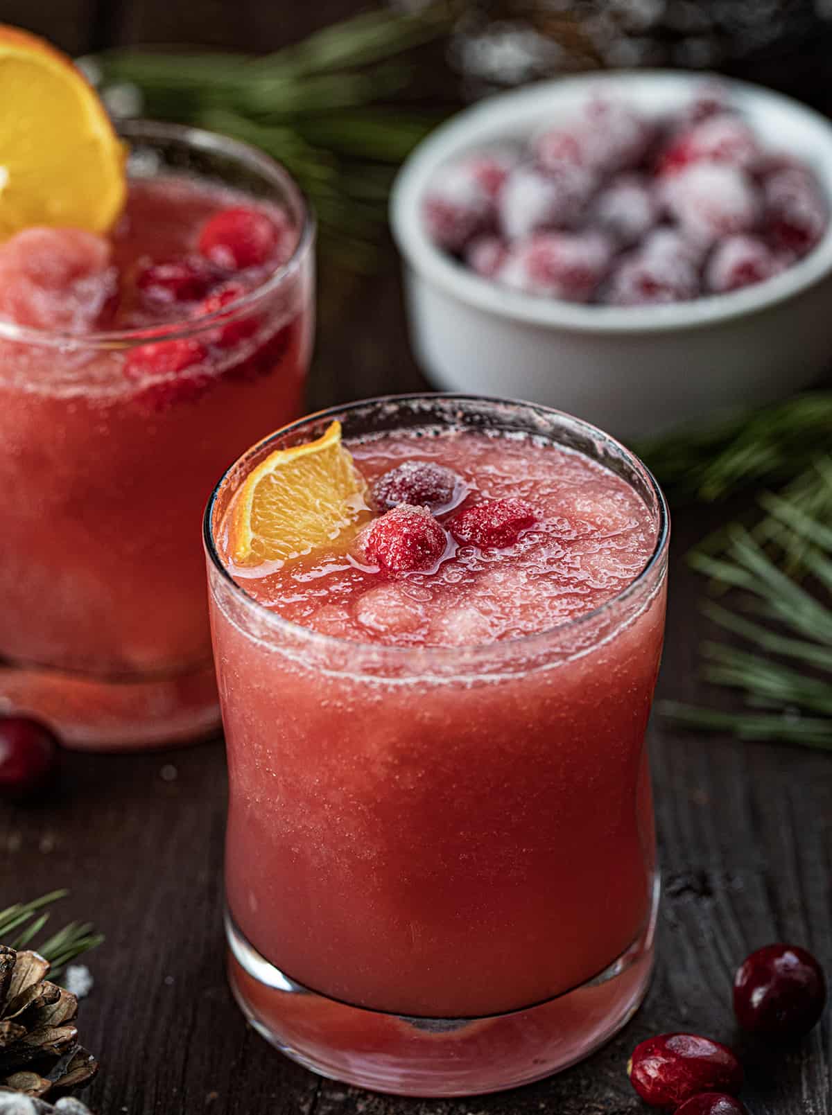 Glass of Christmas Slush with an Orange Garnish and Sugared Cranberries. 