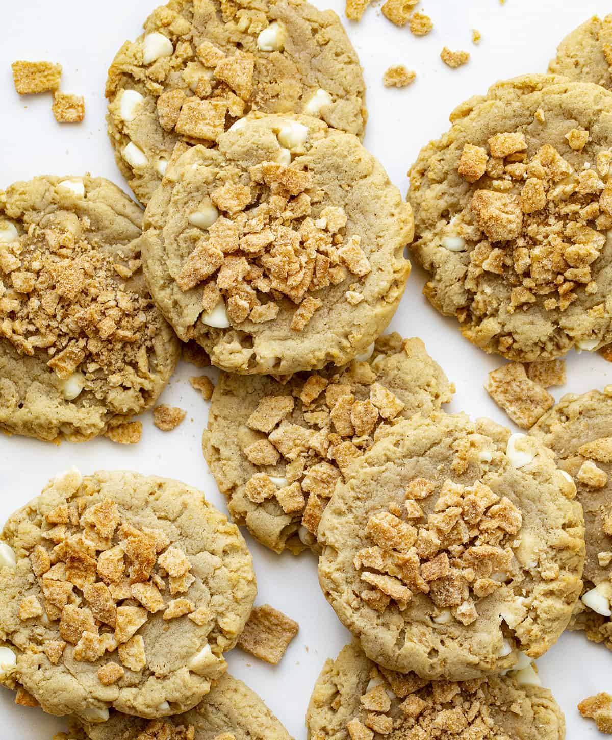 Cinnamon Toast Crunch Cookies on a White Surface with Cereal Sprinkled Around them.