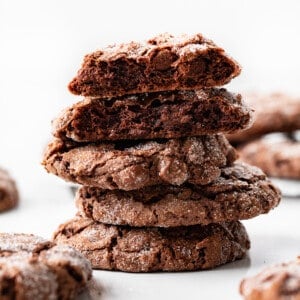 Dirty Chocolate Cookies on a White Counter with One Cookies Broken Showing the Inside Texture.