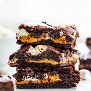 Stack of Fluffernutter Brownies on a White Counter with Marshmallows and More Brownies Around it.