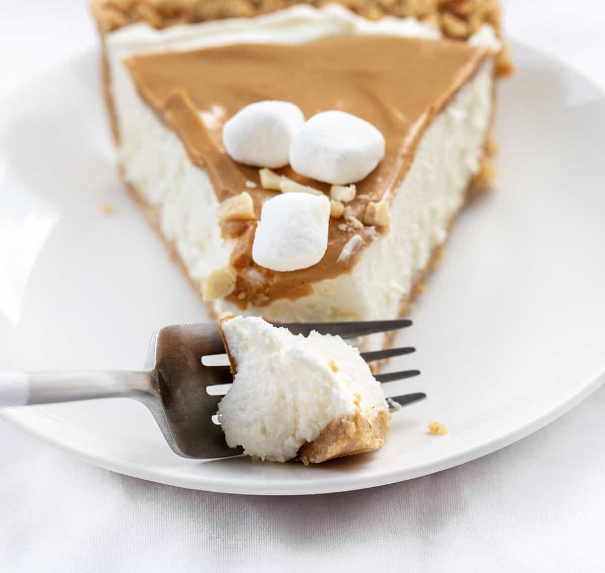 Fork Taking Bite from One Piece of Fluffernutter Pie on White Plate.