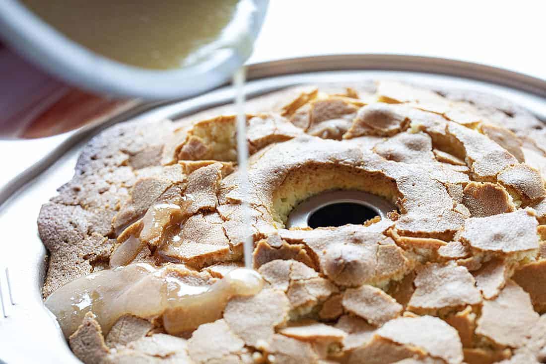 A perfect buttery pound cake with the most delicate crumb is topped with a pecan butter glaze. It's a SHOWSTOPPER!! pound cake, cake baking, kentucky butter crunch cake, kentucky butter cake, butter cake, iambaker, kentucky cake, butter crunch cake, dessert, best desserts, best cake Pouring Butter Glaze over Kentucky Butter Crunch Cake