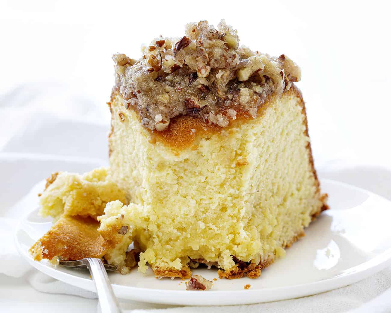 A perfect buttery pound cake with the most delicate crumb is topped with a pecan butter glaze. It's a SHOWSTOPPER!! pound cake, cake baking, kentucky butter crunch cake, kentucky butter cake, butter cake, iambaker, kentucky cake, butter crunch cake, dessert, best desserts, best cake Slice of Kentucky Butter Crunch Cake with a Bite Removed