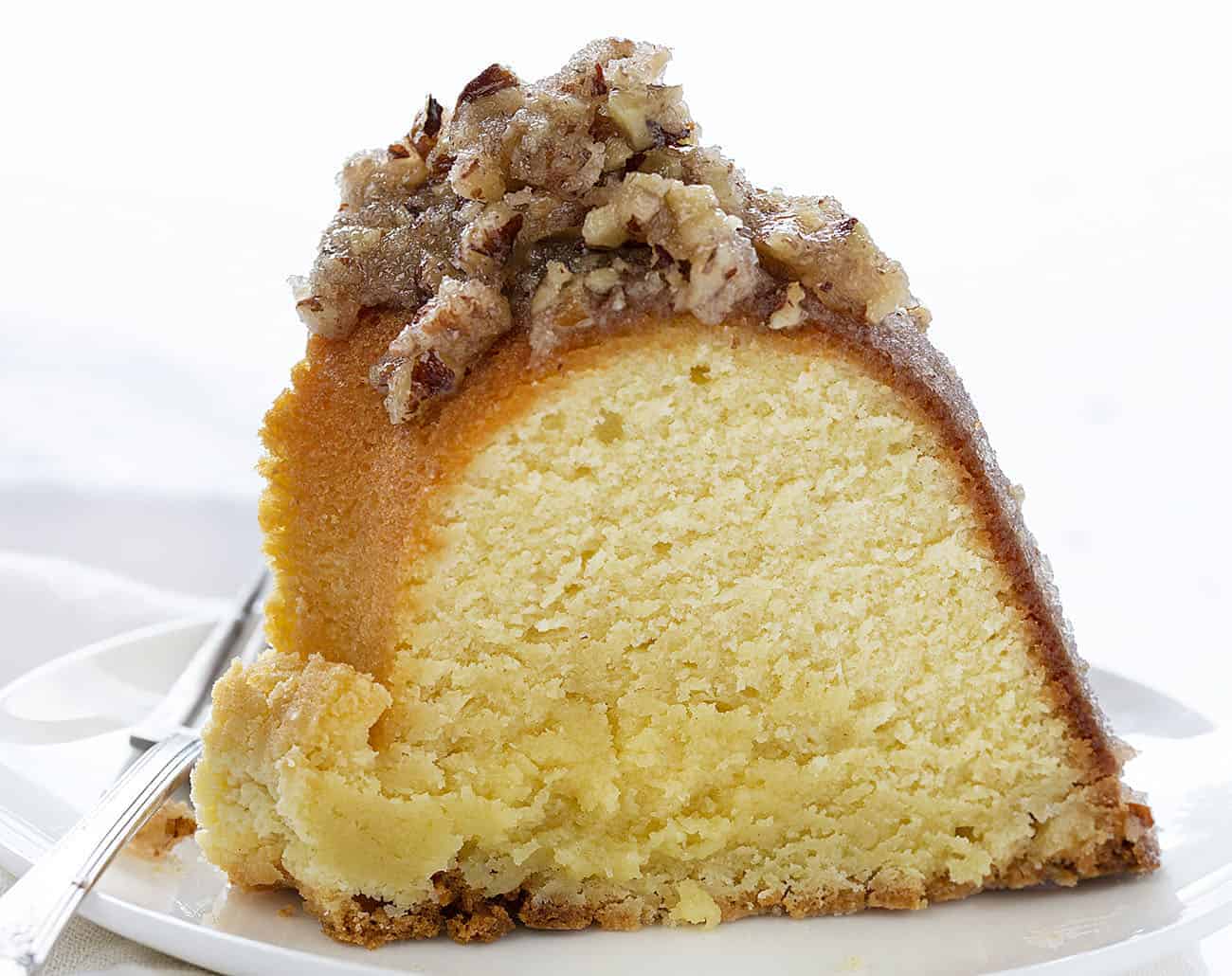 A perfect buttery pound cake with the most delicate crumb is topped with a pecan butter glaze. It's a SHOWSTOPPER!! pound cake, cake baking, kentucky butter crunch cake, kentucky butter cake, butter cake, iambaker, kentucky cake, butter crunch cake, dessert, best desserts, best cake Slice of Kentucky Butter Crunch Cake