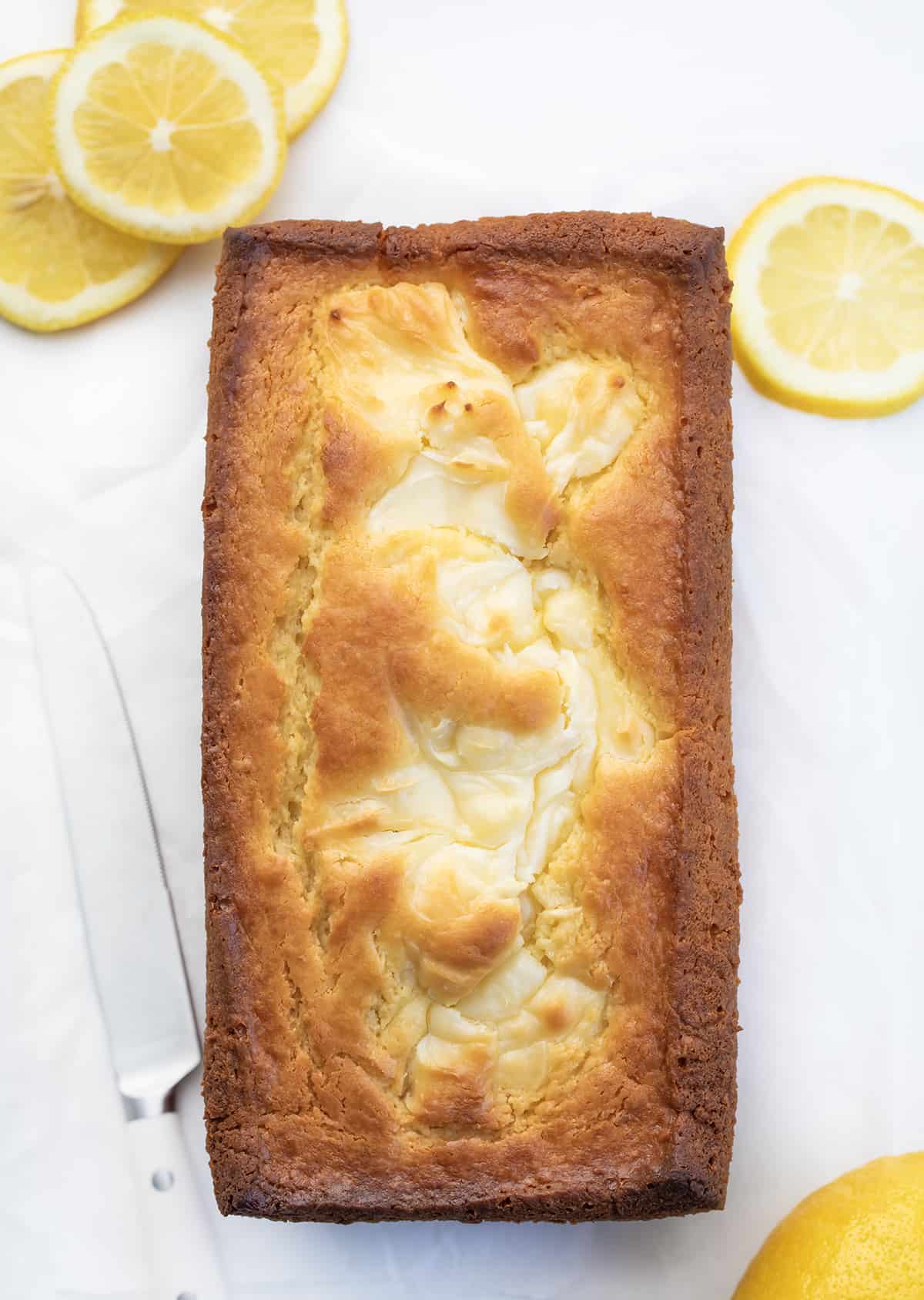 Overhead of a Lemon Cream Cheese Loaf on Counter with Lemons.