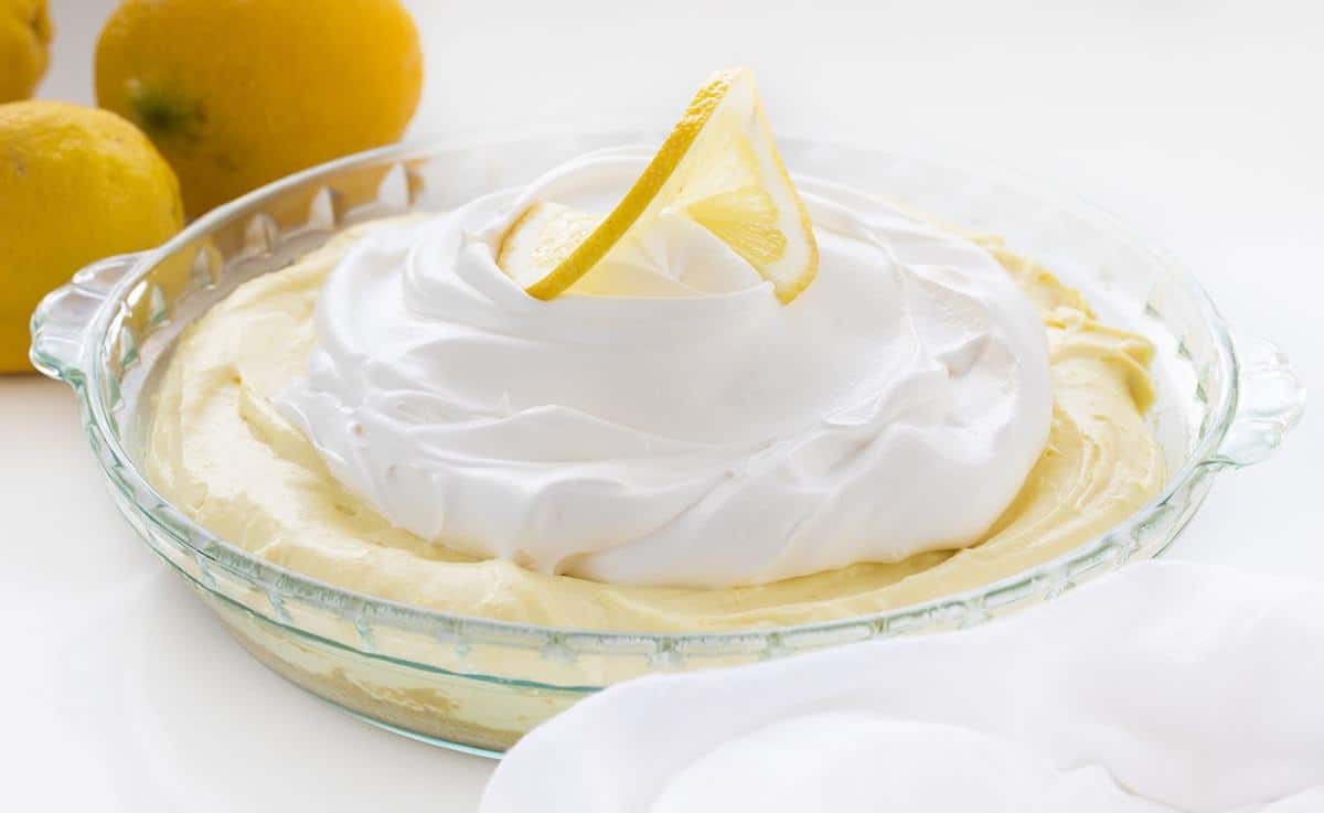 One Lemonade Pie in Glass Pie Pan with Lemons Behind It