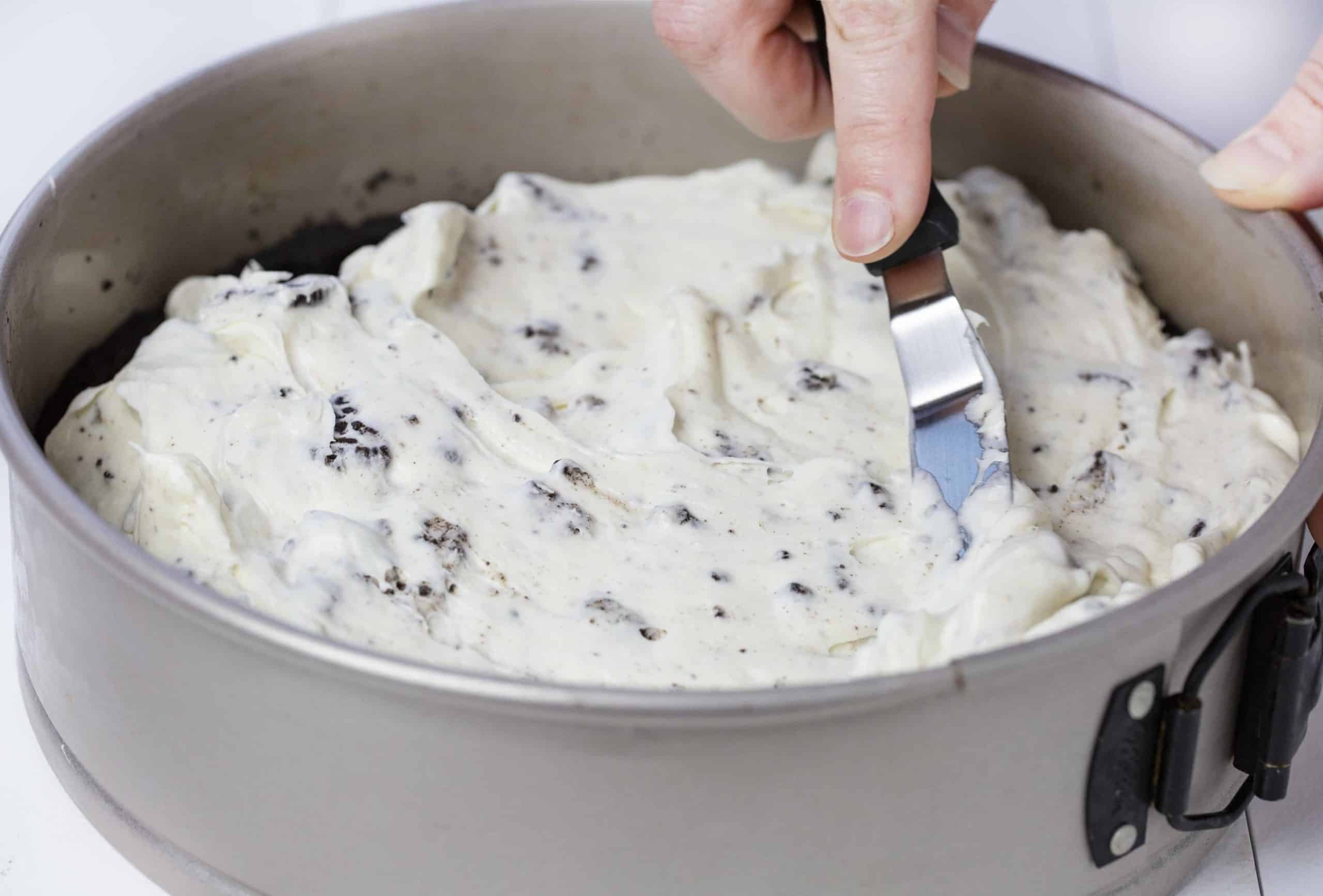 Cream Cheese Mixture Being Spread on No Bake Oreo Cheesecake