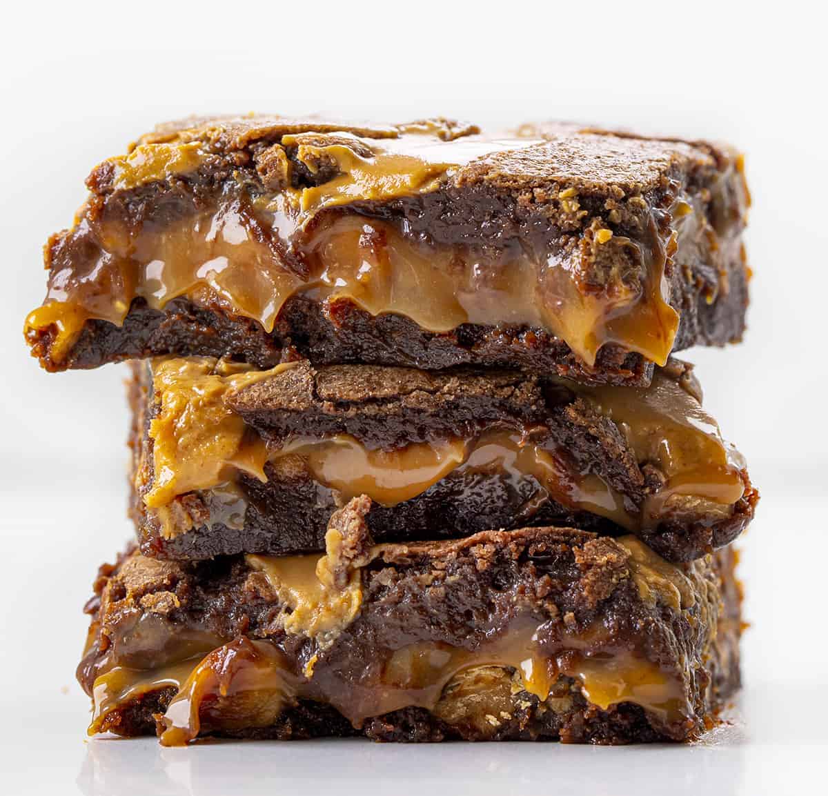 Peanut Butter Brownie Caramelitas are the ULTIMATE ooey gooey brownie! They have a sweet caramel center, along with a layer of peanut butter morsels with more peanut butter drizzled on top. Baking, Brownies, Brownie Recipe, Dessert, Peanut Butter Dessert, Caramel Dessert, dessert recipes, decadent desserts, ooey gooey desserts, i am baker, iambaker Stack of Peanut Butter Brownie Carmelitas