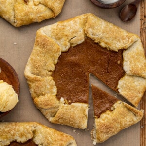 Homemade Pumpkin Galettes on a Cutting Board Uncut and Next to Whipping Cream and Ice Cream. Dessert, Thanksgiving, Pumpkin Pie Galette, Easy Pumpkin Dessert, How to Make Pumpkin Galette, Holiday Desserts, Easy Dessert, Pie Crust, Galette, i am baker, iambaker