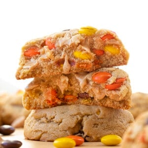 Stacked Reese's Pieces Peanut Butter Cookies and Top Cookie Broken in Half Showing Inside.