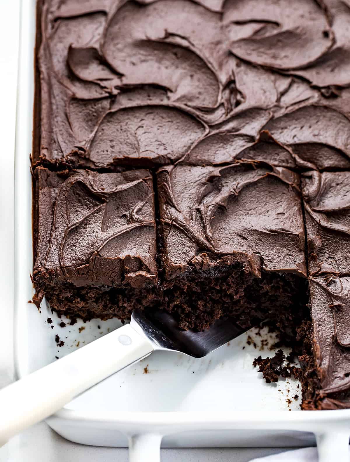 Pan of Chocolate Sauerkraut Cake with Two Pieces Missing and the Spatula in the Pan.