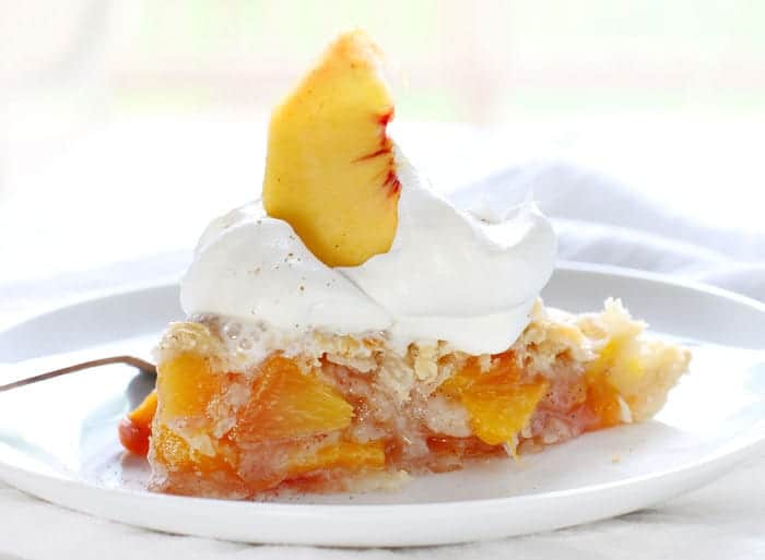 The perfect slice of peach pie with whipped cream and peach garnish!