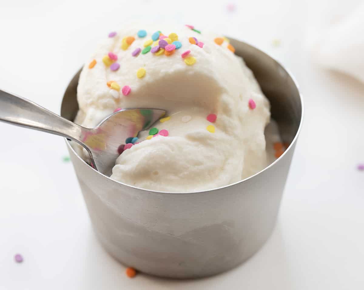 Spoon Taking a Bite out of a Metal Dish with Soft Serve Ice Cream.