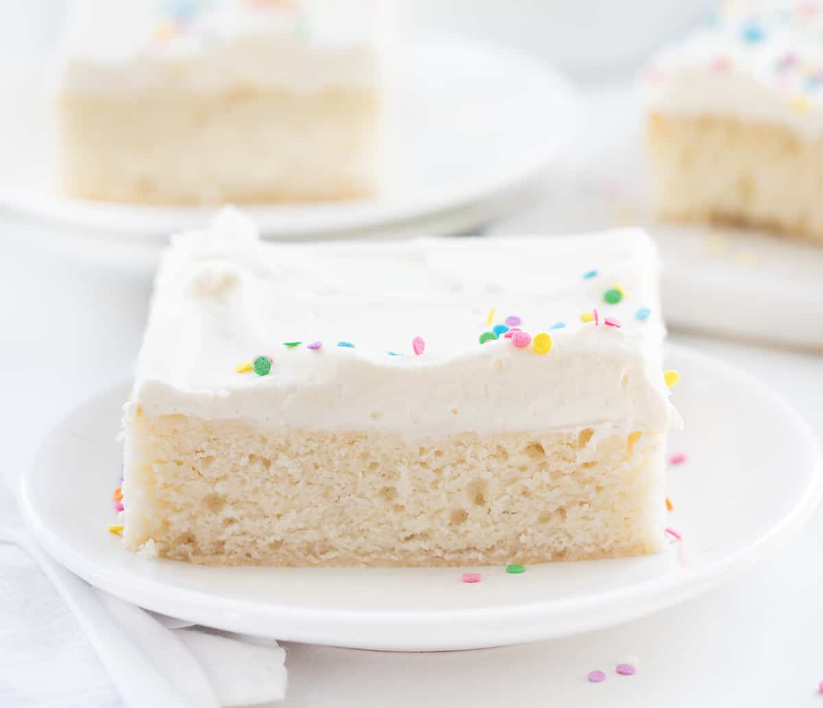 Piece of Vanilla-Delight Cake or White Cake on a White Plate with More Plates in the Background.