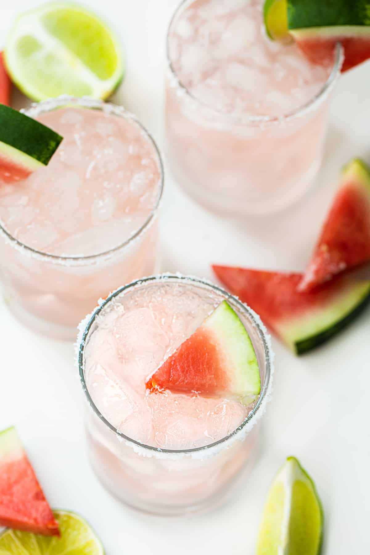 Glass Filled with a Watermelon Refresher Cocktail with a Watermelon Wedge and Lime.