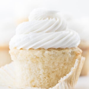 White Cupcake with Wrapper Removed Showing Texture of Cupcake and Covered in Vanilla Frosting.