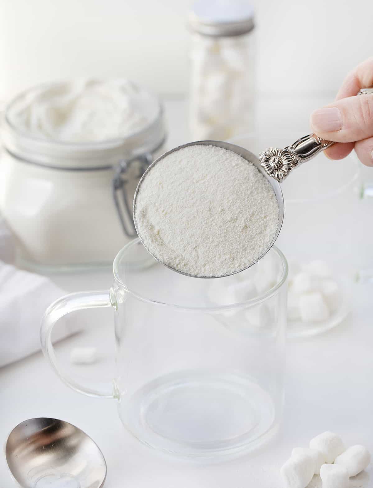 Measuring cup with white chocolate cocoa powder in it about to be pouring in a glass.