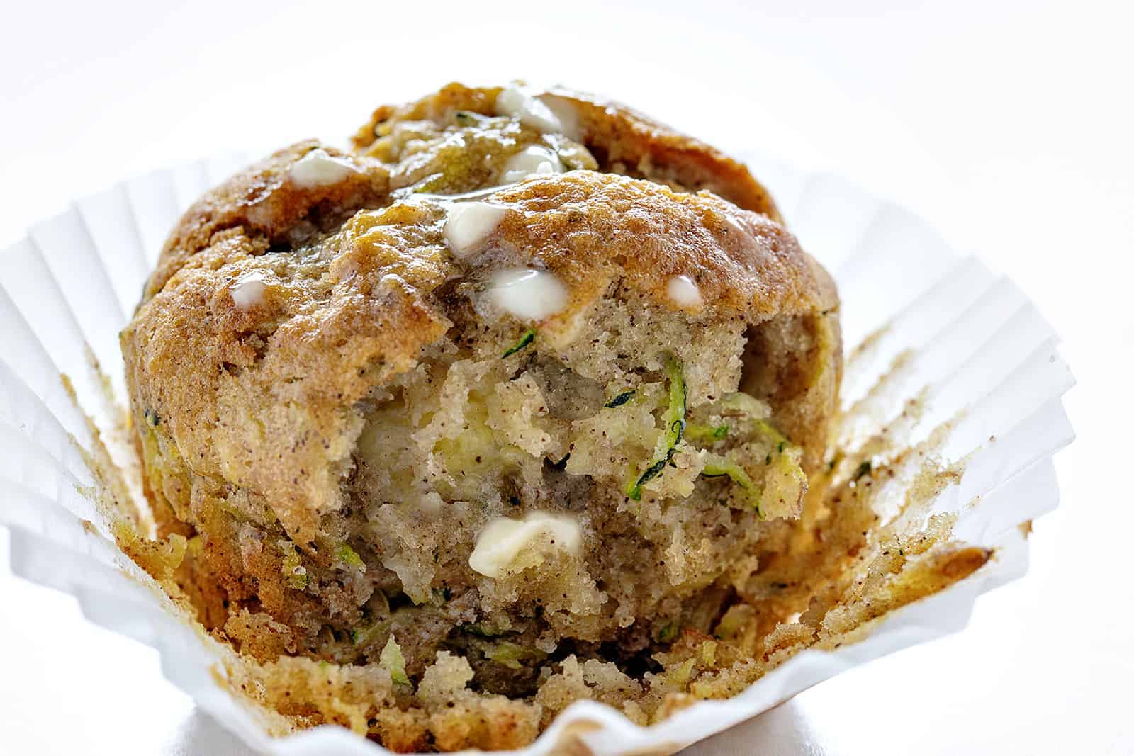 Banana Zucchini Muffins are so moist and delicious, you will never think of buying a muffin again! banana zucchini muffins, zucchini muffins, banana muffins, homemade muffins, iambaker, baking, muffins, bananas, zucchini recipes Banana Zucchini Muffin with Melted Butter And A Bite Taken Out on a Cupcake Liner.